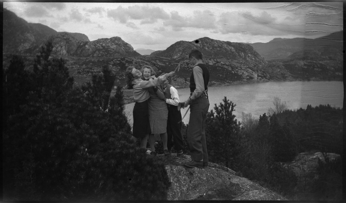 Jon Madland, Harry Nilsen og to jenter på sykkeltur til Lutsi. Det er bilder av barna på fjellet med Lutsivatnet i bakgrunnen . Guttene bytter på å holde et gevær.