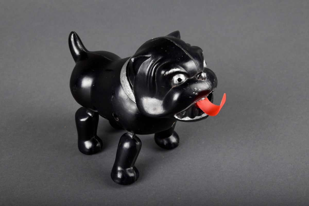 Svart bulldog med trekkopp-mekanisme. Trekkes opp ved å dra i tungen.