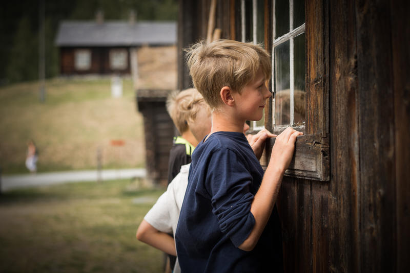 To barn ser gjennom vindauge til eit gamalt hus