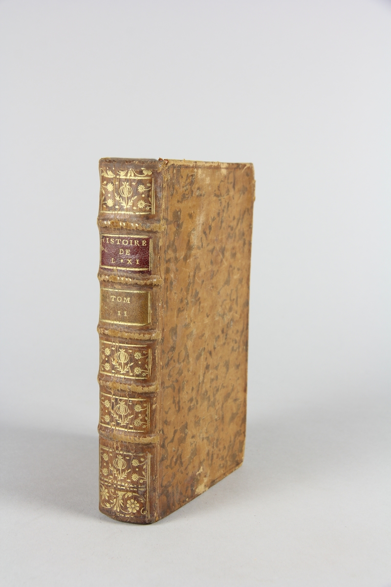 Bok, "Histoire de Louis XI",  del 2. Skinnband med guldpräglad rygg i fem upphöjda bind, fält med titel och volymens nummer. Marmorerat papper på pärmarnas insidor. Rött snitt.