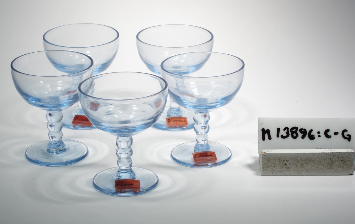 Likörglas tillhörande likörsats.
Rund fot, ben bestående av tre kulor.
Blått klarglas.
Inskrivet i huvudkatalogen 1944.
Funktion: Likörglas