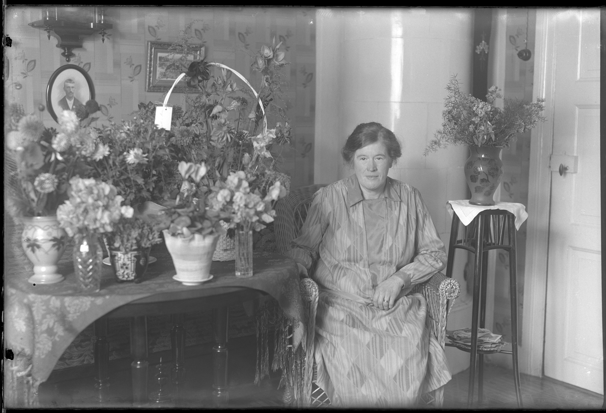 Fru Hallgren fotograferad omgiven av blommor i samband med sin 50årsdag. Tolkat som Hilda Elisabeth Hallgren (f. Kämpe).