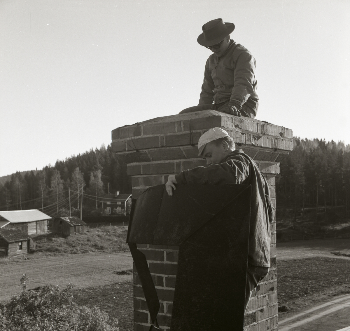 Två män arbetar intill en skorsten, 1967.