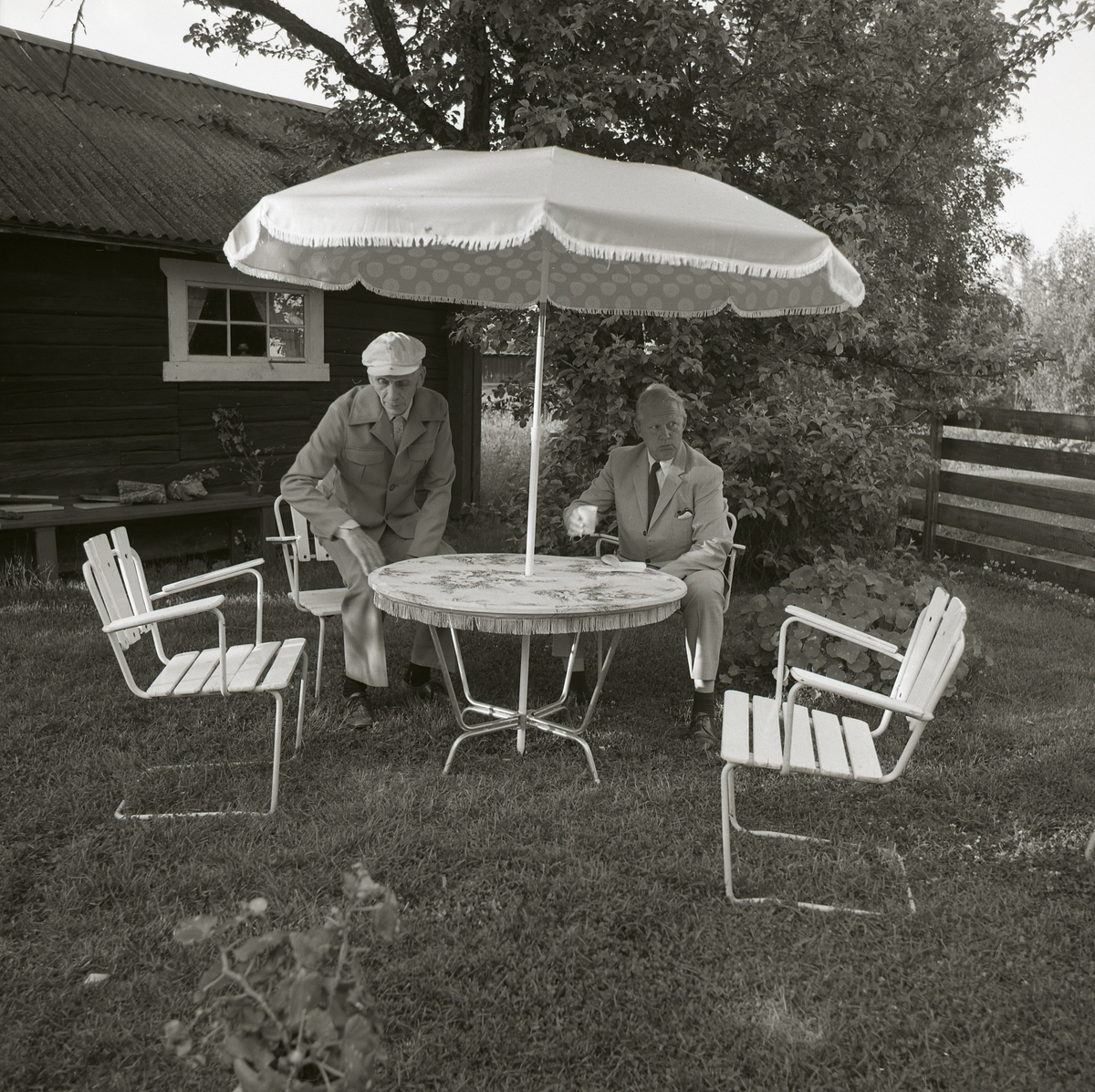 Bo Setterlind hos kyrkoherde Hans Persson, Långvind  22 juli 1984. Två män under parasoll i trädgården.