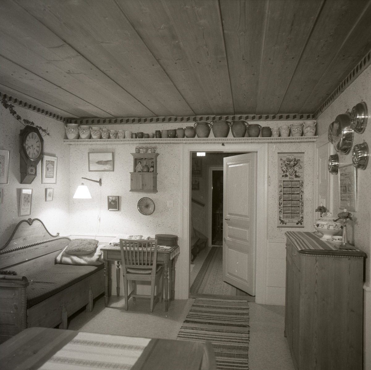 Ett rum med soffa, krukor, byrå och väggklocka på Sunnanåker.