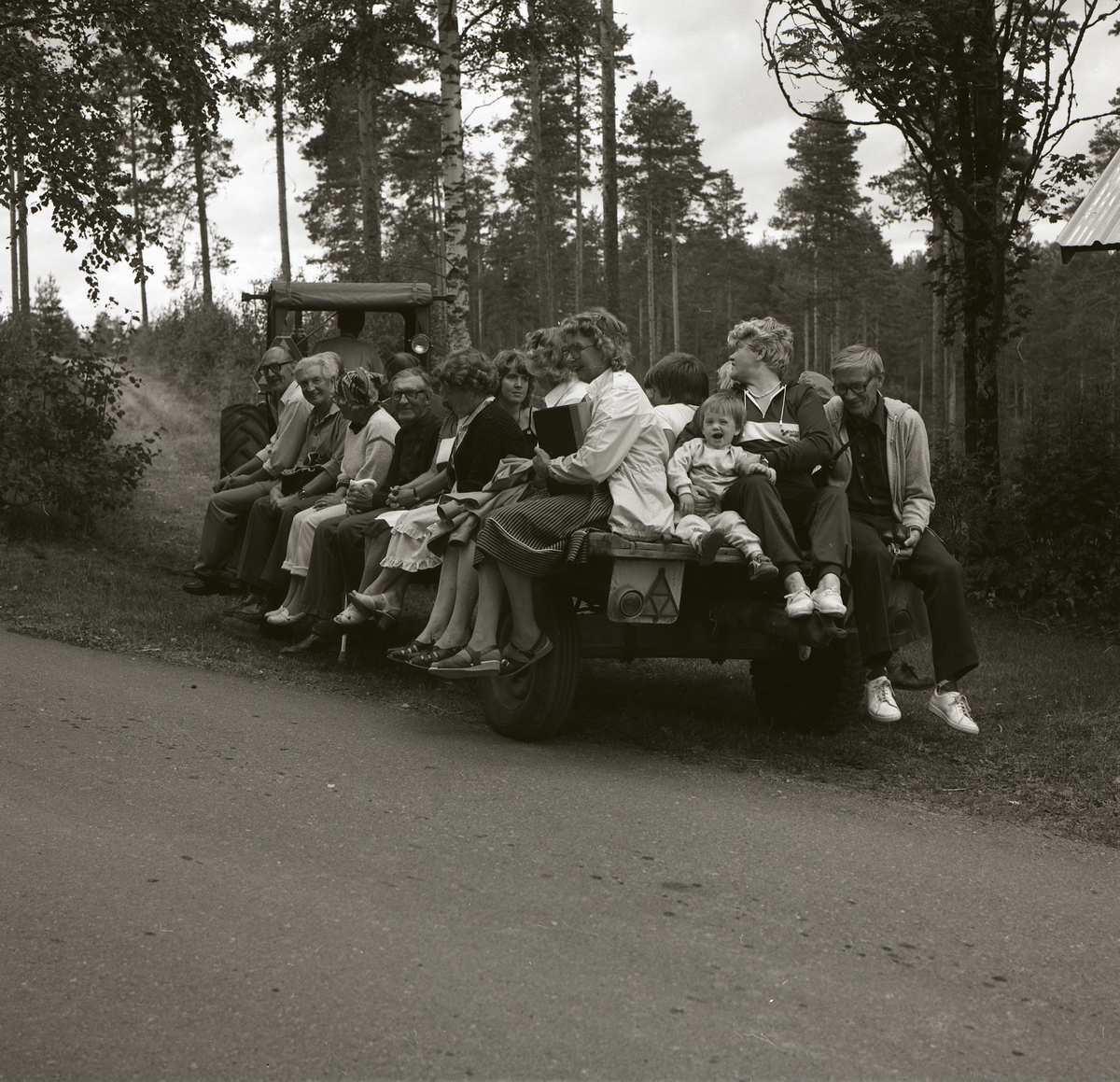 På ett traktorsläp sitter män, kvinnor och barn för att åka på byvandring i Östra Höle, 27 augusti 1983.