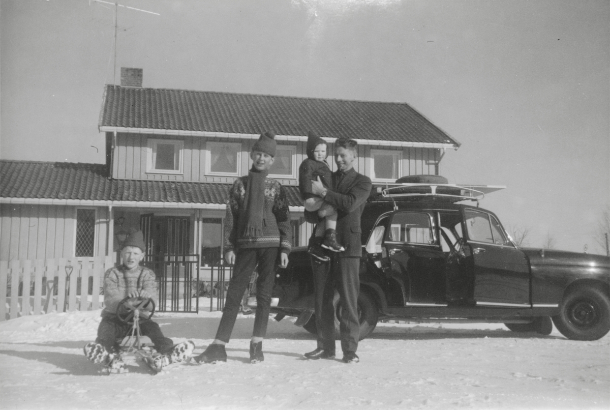 Vinterkledd familie med rattkjelke og bil utenfor hovedhuset på Bråte gård i Gjerdrum.