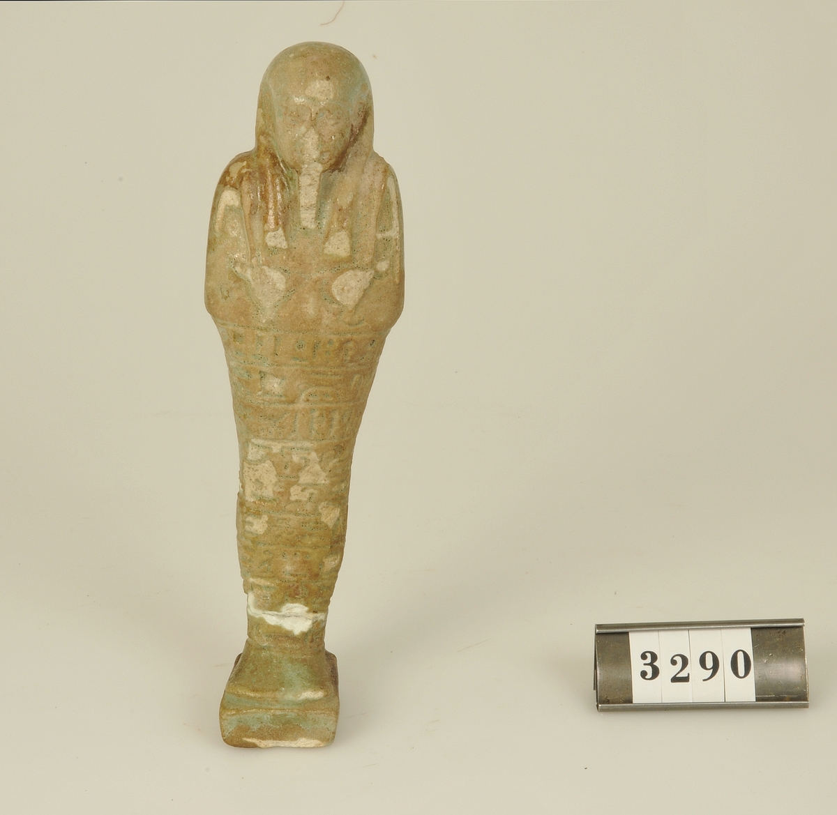 Av fajans med grönaktig glasyr.
Nedre delen av figuren täckt med hieroglyfer.

Har tillhört de Adelsköldska samlingarna.
