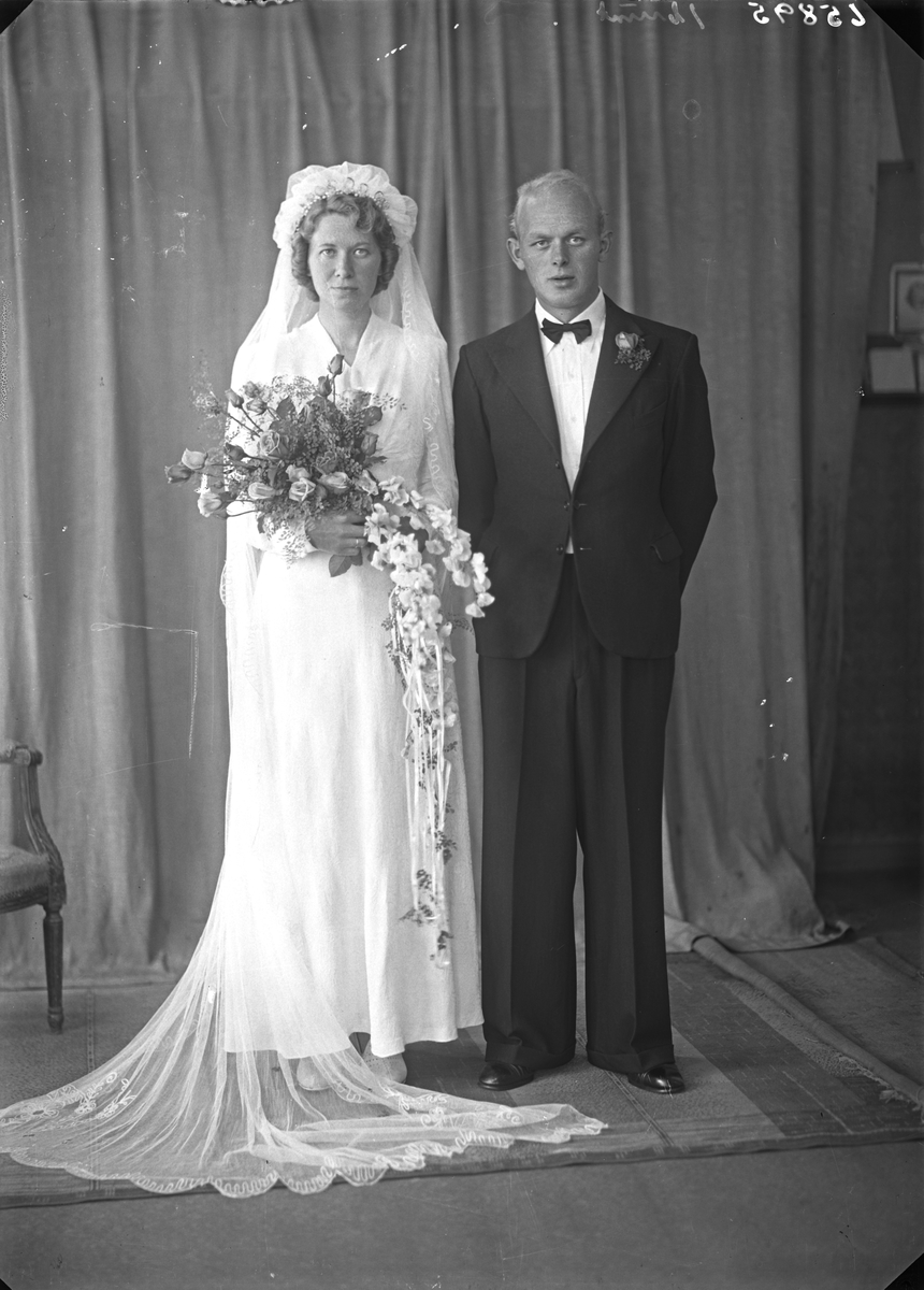 Portrett. Ung kvinne i hvit brudekjole med blomsterbukett og ung mann i mørk dress. Brudepar. Bestilt av Johannes T. Skåren. Utsira