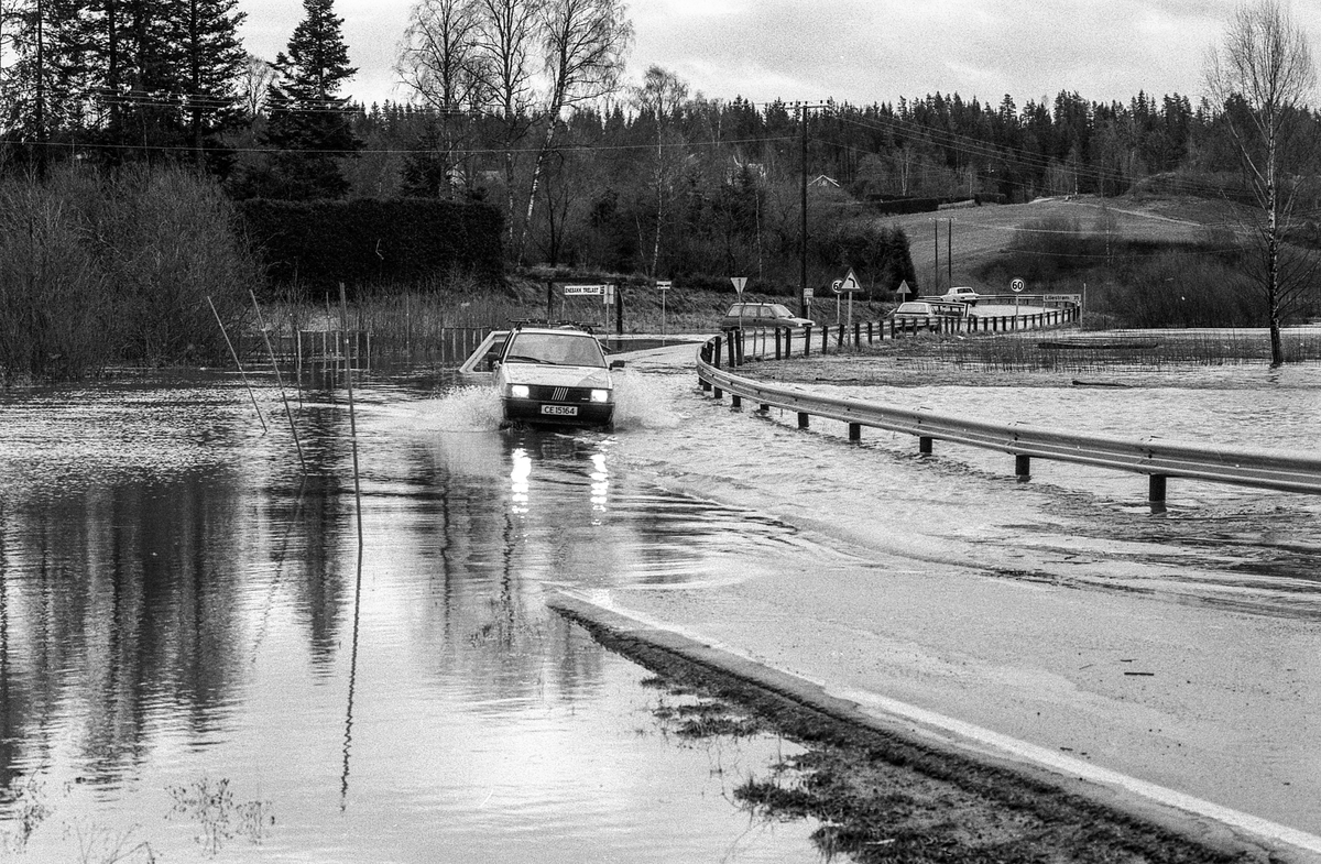Flom i Enebakk over veier og jorder, biler kjører i flomvannet.