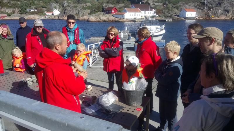 Arkeolog viser frem funn fra sjøbunnen til en gruppe besøkende på brygga. (Foto/Photo)