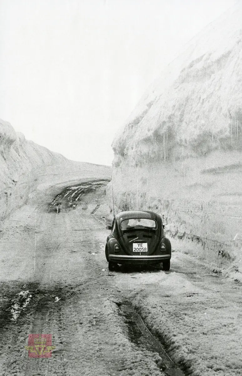 Høye brøytekanter på Saltfjellet. På vegen en Folkevogn Volkswagen 1300 og bak rattet sitter Hans Sand. Brøytekantene var 13 meter. Fotografert mai 1973. I følge merking til bildet.