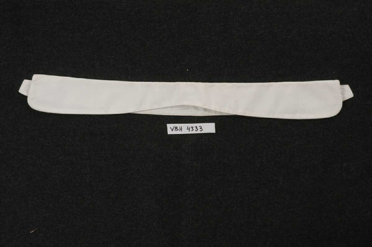 Skjortesnippen er sydd av hvit bomullslerret. Stikning langs kantene. Dobbel snipp, brettes ned langs kantene. Knapphull midt bak og i endene.