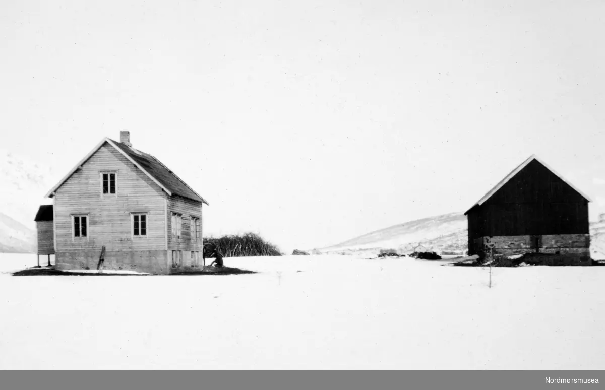 Foto av et gårdsbruk en vinterdag. Et bilde fra en samling fotografier med bureisingsfelt i Norge. Originalmaterialet tilhører Norsk myrmuseum i Smøla kommune. Fra Nordmøre museums fotosamlinger.
