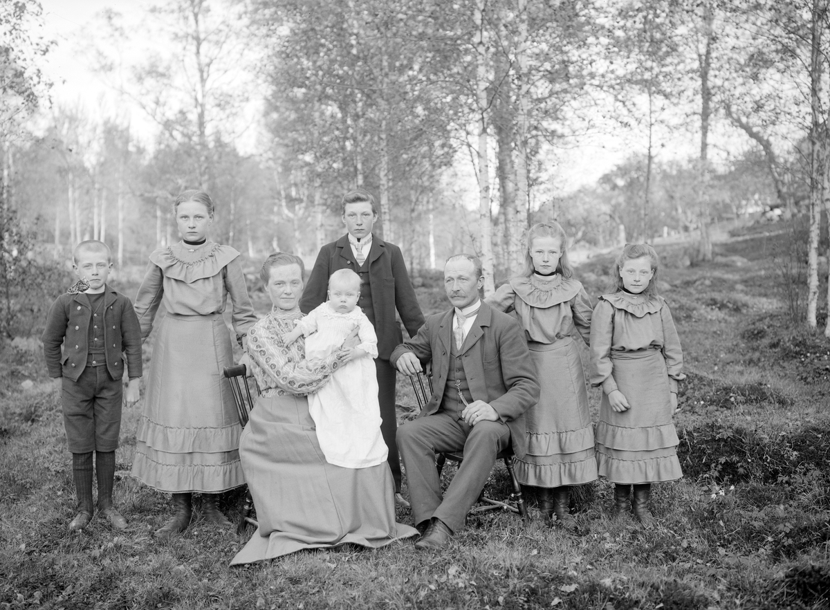 Makarna Konrad och Karolina Albertina Andersson med sina sex barn. Paret är hemmansägare i Idhult, maken dessutom kyrkvärd. Bilden är odaterad men yngste sonen i moderns famn är född i augusti månad 1905, vilket rimligtvis förlägger fototillfället till våren 1906.