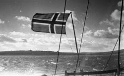 Det Norske flagget vaier i vinden. Suderøy på vei til fangst