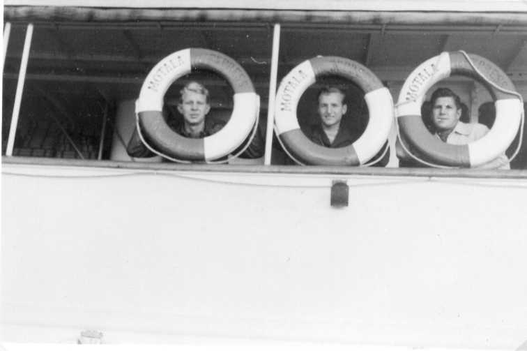 Tre unga män kikar ut genom livbojar ombord på Motala Express. Bojarna är märkta "Motala Express".