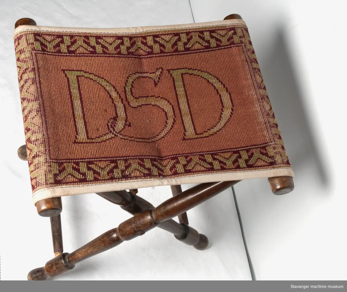 En taburett i tre og tekstil, med DSD logo på setet.