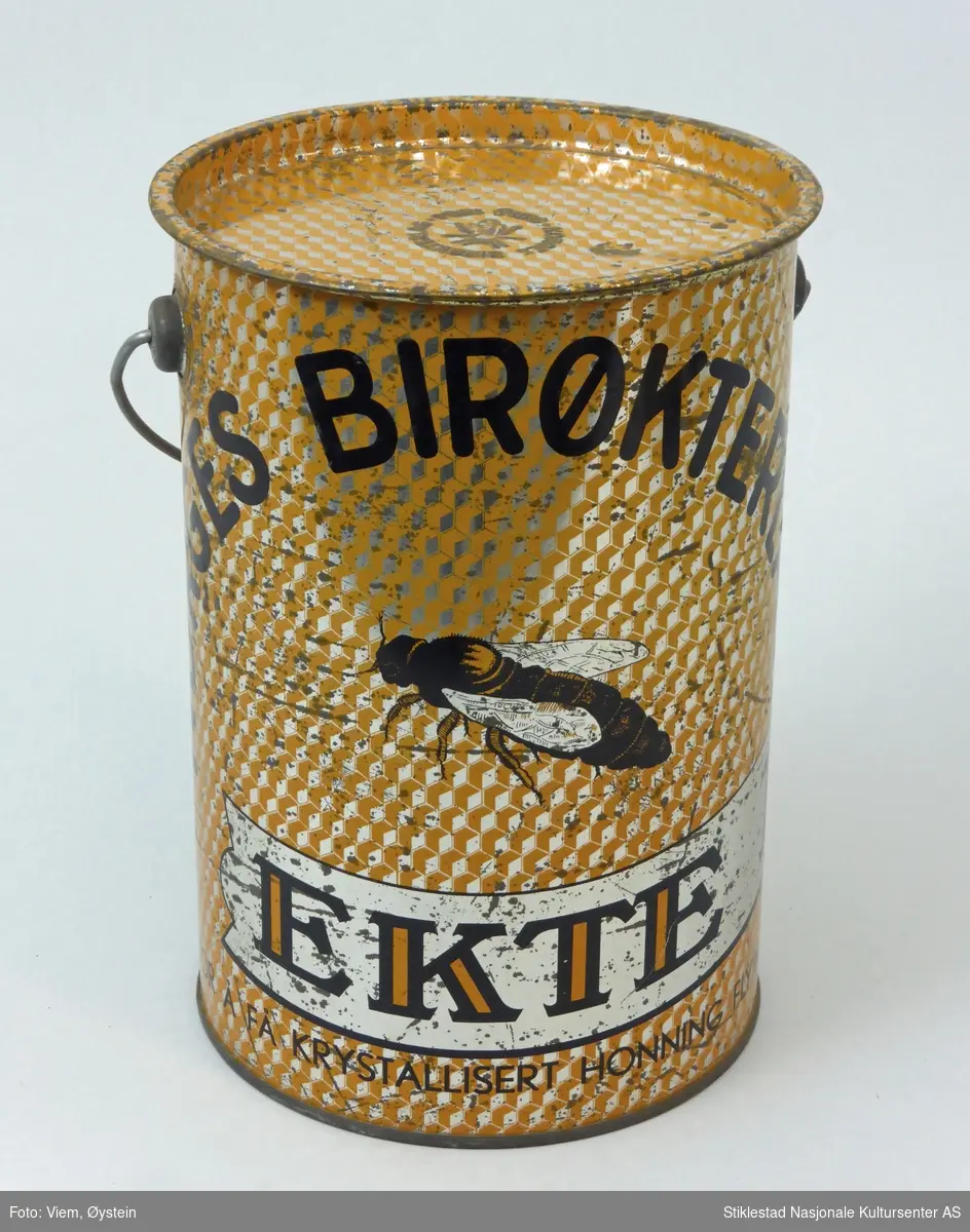 Blikkspann for honning med hank og lokk. Merket NORGES BIRØKTERLAG. EKTE HONNING, gulfarget boks.