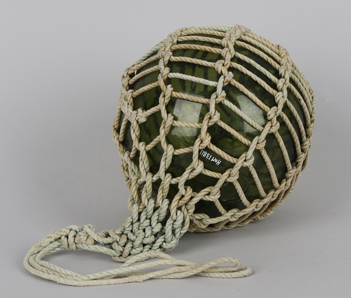 Garnblåse i grønt glass med garn bundet i et nett rundt, kavelhue eller kavelhud. Den har dobbel løkke.