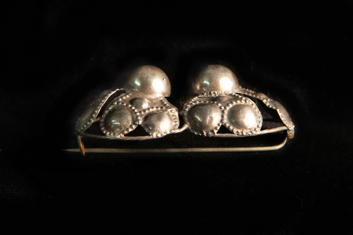 Ett par hoptvinnade maljor av ciselerat silver och delvis genombrutet silver med prickdekor m.m. Spännet, maljan, har gjorts om till en brosch.