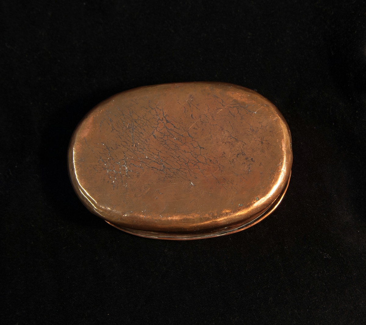 En oval tobaksdosa av koppar. Förtennat inuti. På locket tremblerade initialer och årtal: "P:S:D: 1791".