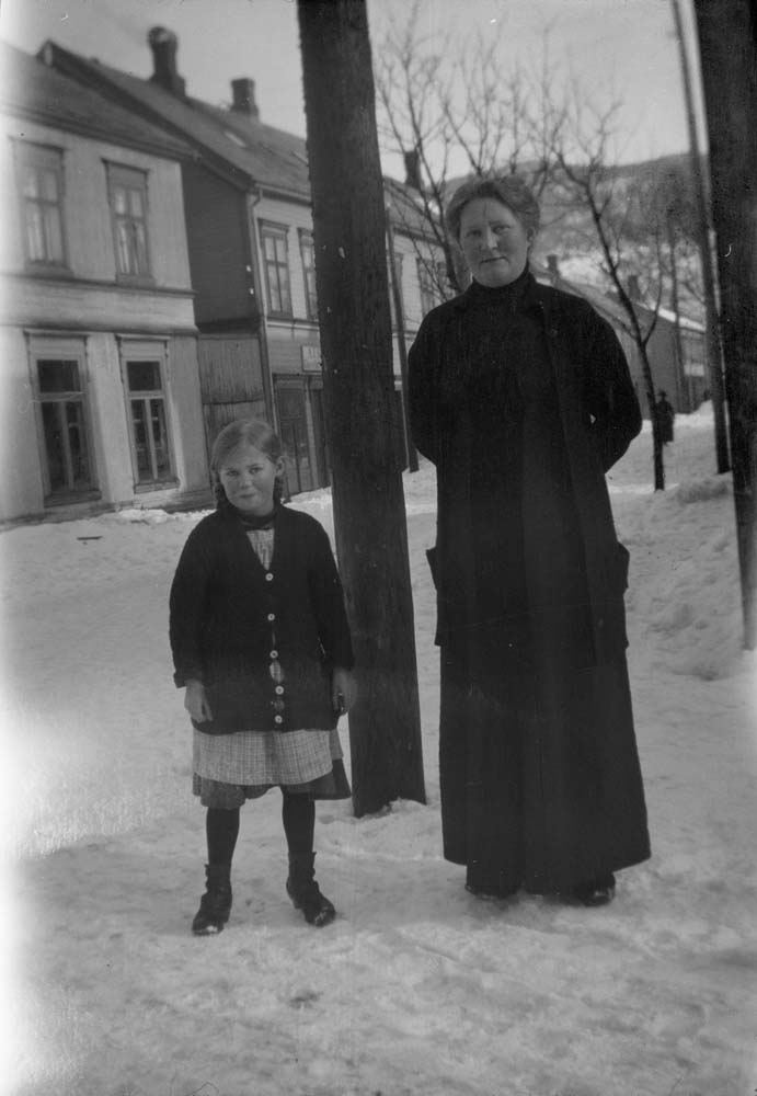 Kvinne og jente står i snøfylt gate.