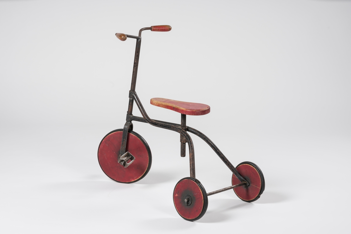 Form: Ramme av hulrør, forhjul med pedaler, flatt, innsvinget sete.
