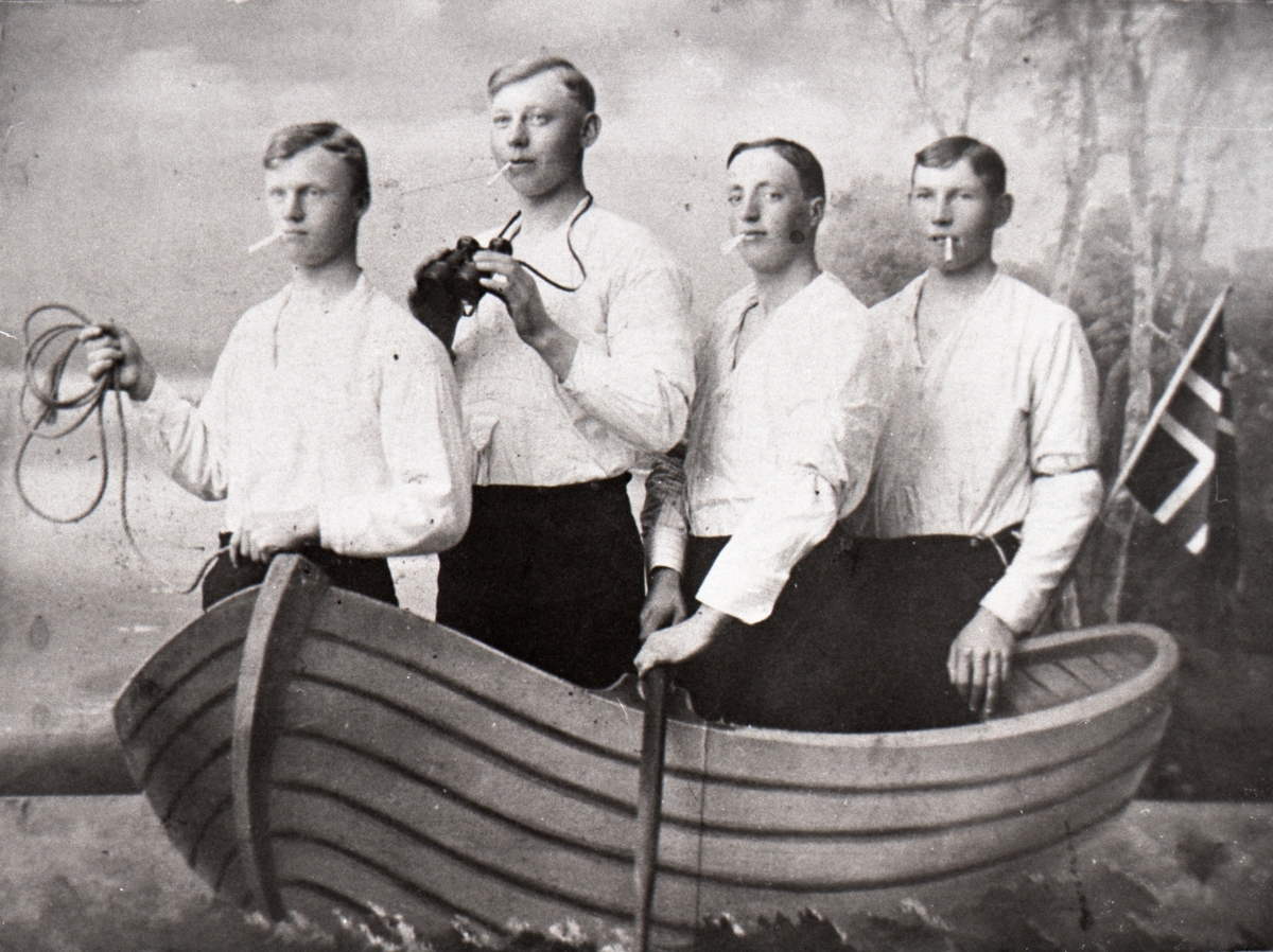 Gruppeportrett av 4 unge menn i en kunstig båt i et fotostudio.