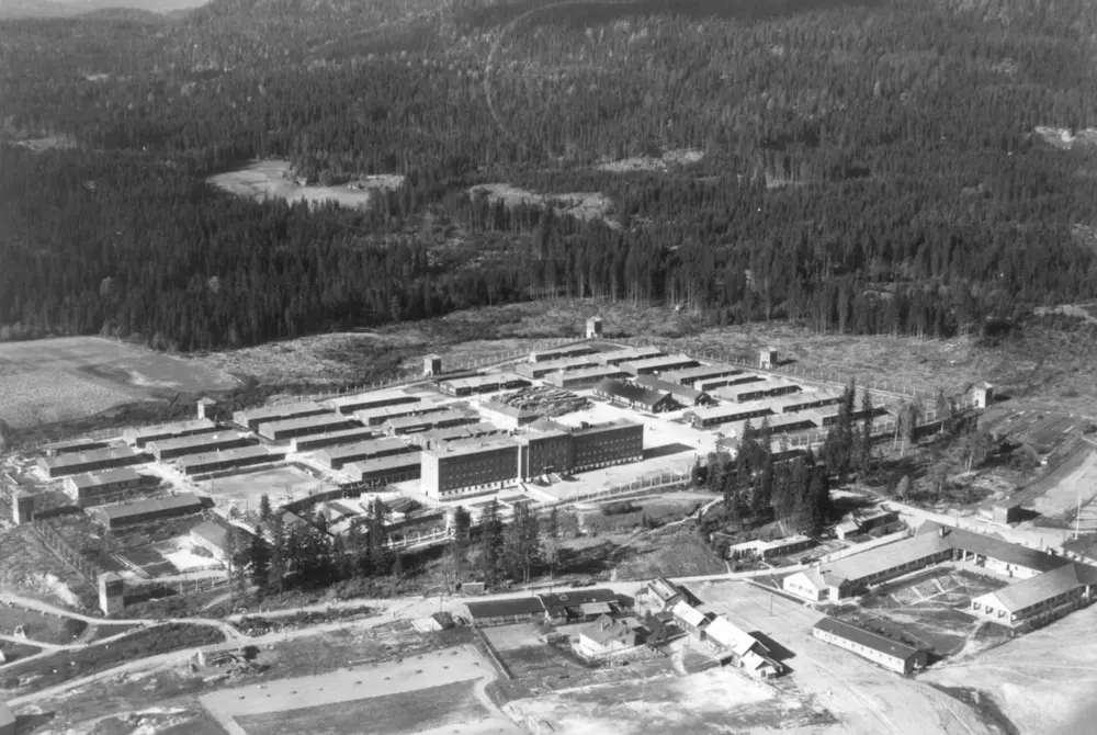 Photo of Grini prison camp seen from above. Main buliding in the foreground with the barracks behind.