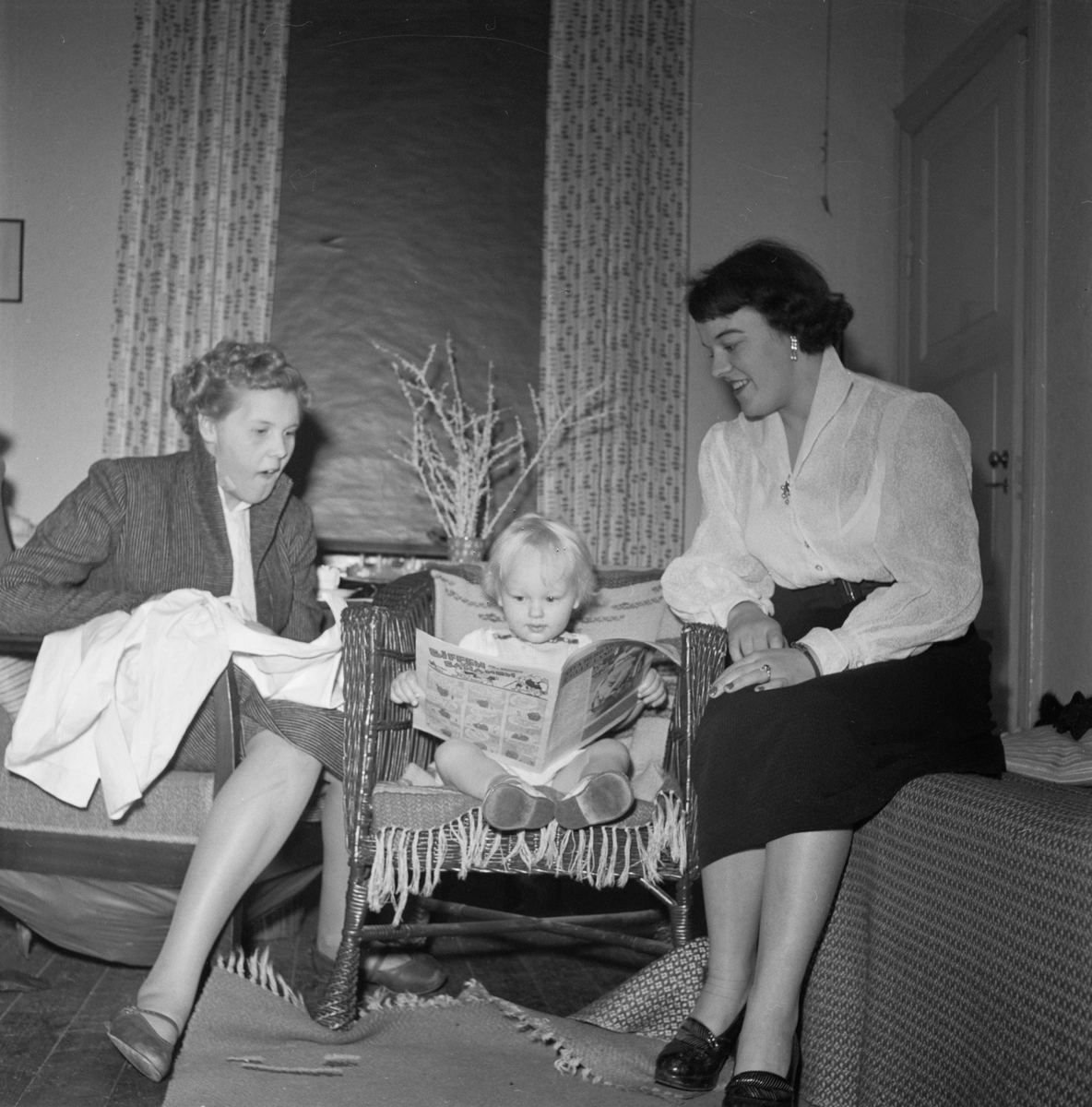 Två kvinnor och en pojke tittar i en tidning, Uppsala 1952
