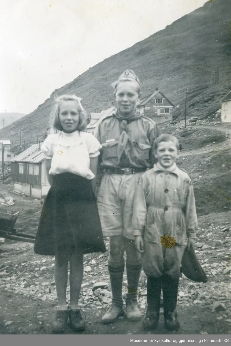 Honningsvåg. Søskene Berit, Cato (i speideruniform) og Ole Grøtta. Gjenreisningsbebyggelse i bakgrunnen. Ca. 1954.