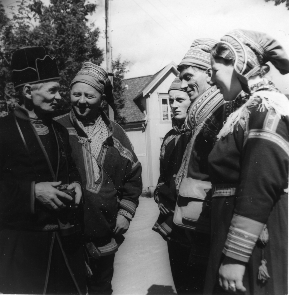 En dame og fire menn kledd i kofter i en felles samtale