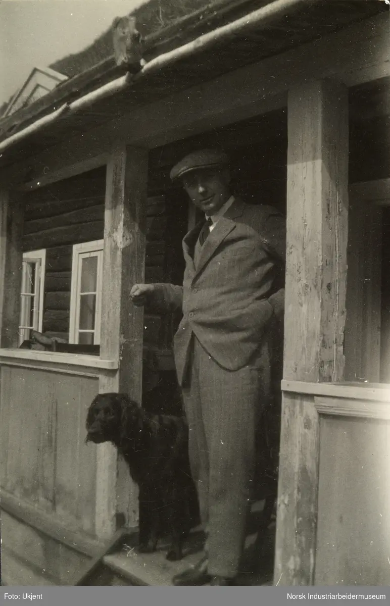 Mann og hund står på øverst på trappen ved hyttedør