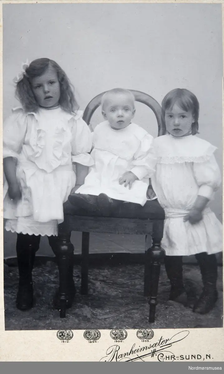 Portrettfoto av tre små barn. Alle er trolig fra Kristiansund. Fra et fotoalbum som stammer etter Marie Opdal (f. april 1894 - d. februar 1981/82), gitt i gave av Torbjørg og Arild Karijord. Fra Nordmøre museums fotosamlinger.