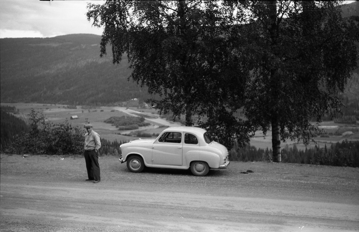 Ole Majer fra Lensbygda foran bilen sin på en rasteplass. Han og Sigurd Røisli er nok på tur. Dalføret i bakgrunnen er trolig langs Etna.