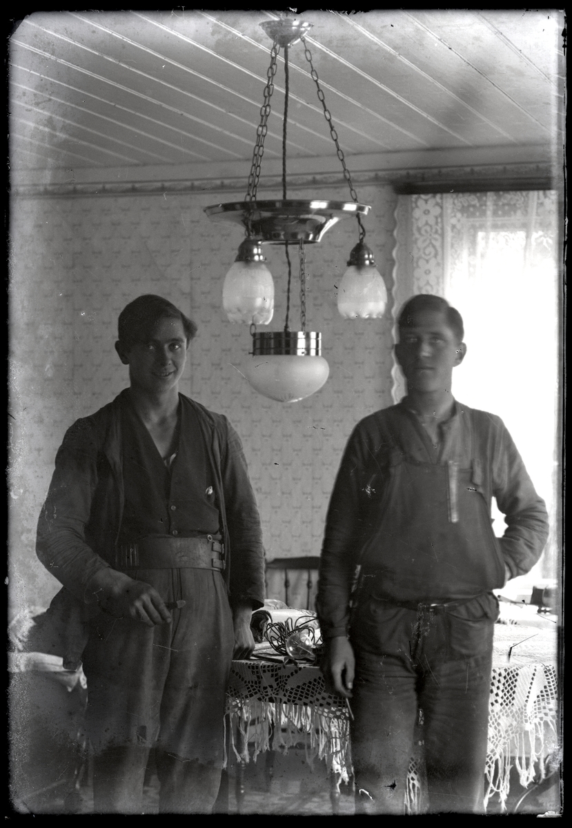 Två unga män under den första elektriska taklampan