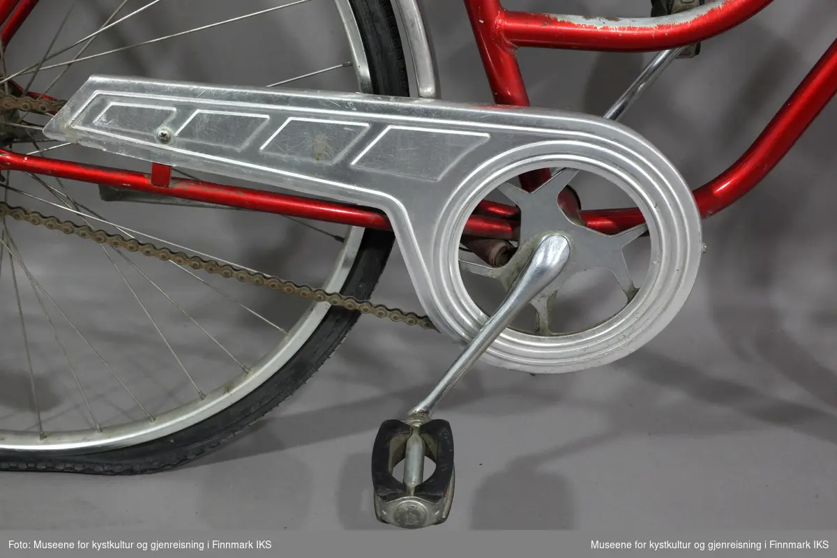 Sykkelen er rød, har et smalt, svart sete, et bagasjebrett, ei kjedebeskytter og en sykkelstøtte. Sykkelen har ei lykt foran, merket "Safir", som drives av en dynamo festet på bakhjulet. På styret er det en spake på venstre side og ei bjelle på høyre side. Bak er de to røde reflekser, en som er en del av sykkelen og en litt større som er festet til bagasjebrettet. Pedalene er enkelt utformet med to gummiklosser festet på hver side av tråkket. Rundt setet er det en kjetting med hengelås. Sykkelen har også et rammelås på bakhjulet. Begge hjulene har to gule reflekser.