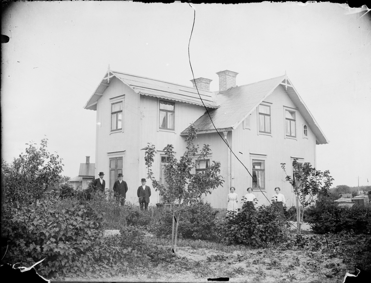 Män och kvinnor i trädgården vid ett bostadshus, Östhammar, Uppland omkring 1910