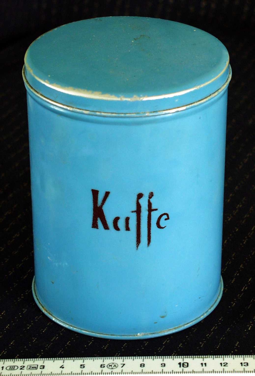 Lys blå/turkis kaffeboks i blikk. Merket med "Kaffe". 
Denne boksen har vært brukt til oppbevaring av salt. Inni ligger en halvfull saltpose.