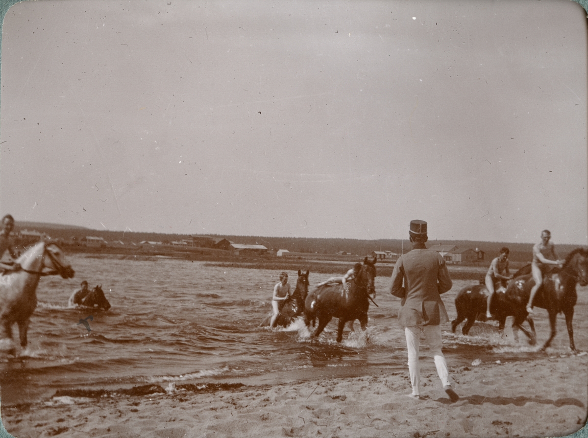 Gruppbild med soldater och hästar vid stranden.
