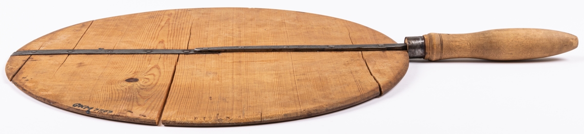 Brödspade av furu med förstärkning tvärs över av järn, svarvat handtag i kanten.