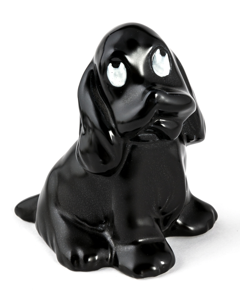 Figurin i svartglaserad flintgods med titeln Ruff. Svart hund i sittande position som tittar uppåt. Ögonen målade vita. Formgivare Dorothy Clough.