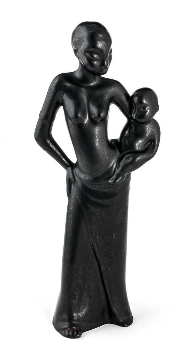 Figurin, "Negress", modell C15. Tillverkad mellan 1955-57. Figurinen helt glaserad i den svarta glasyren Mangania. Föreställer en svart kvinna som håller ett barn på höften.