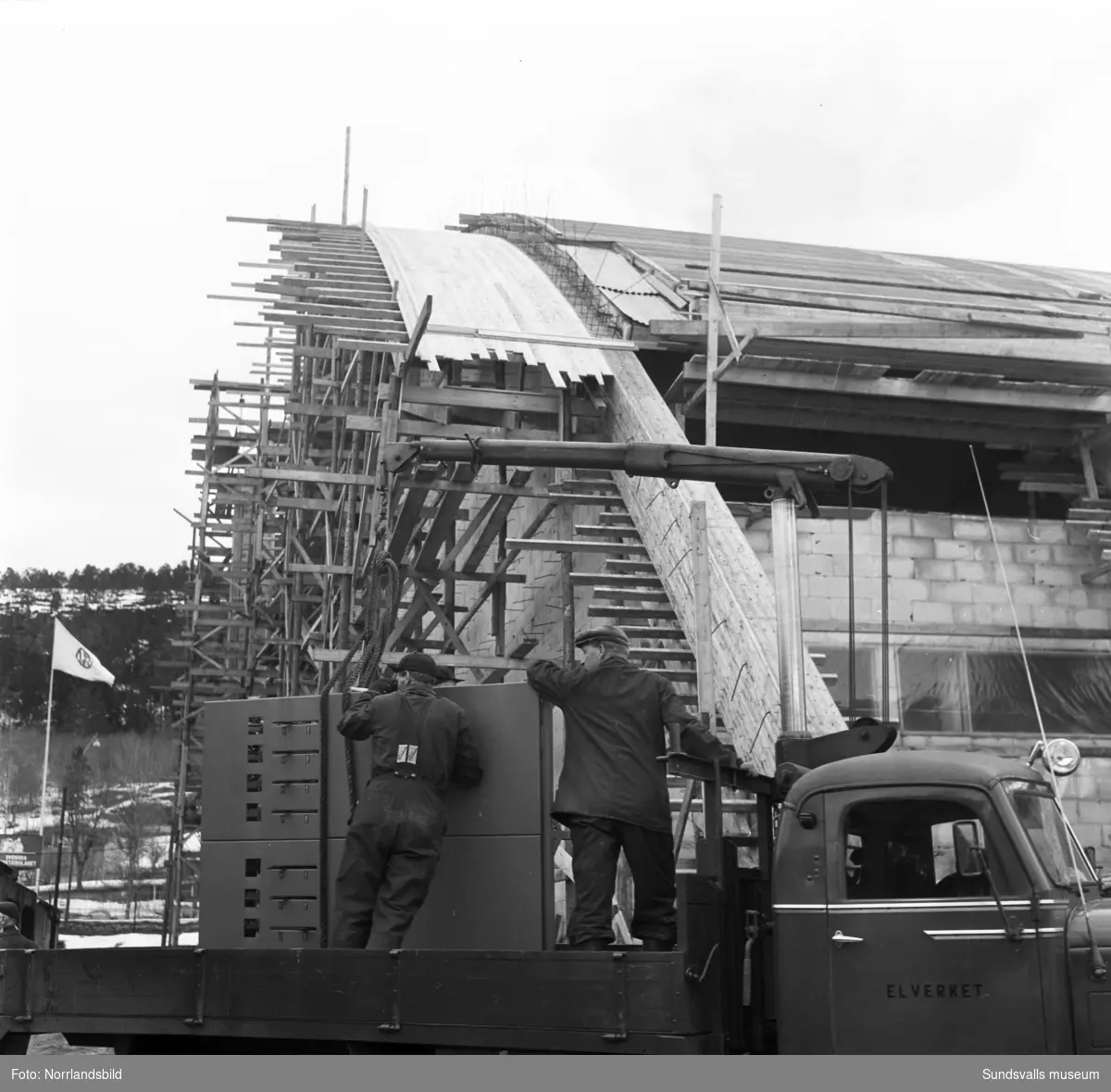 Elverkets manskap levererar utrustning (elcentral?) till bygget av Sundsvalls nya sporthall.På fjärde bilden syns byggnader som tillhört Svensk Papp, senare Browin´s begagnade maskiner.