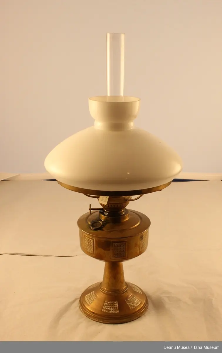 Parafinlampe  i messing som innholder lampeolje. Lampeskjerm i hvit glass. lampeglass i klar glass.