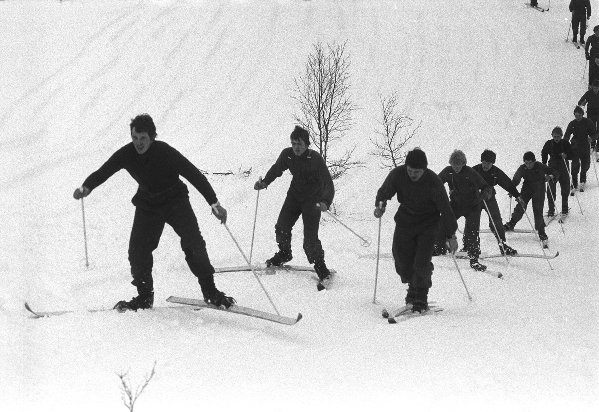 Befalsskoleelever på ski går opp bakke.