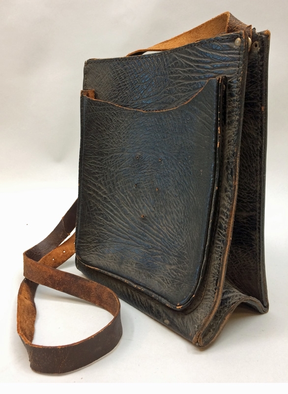Väska av brunt präglat läder, med rem. Ett fack framtill, och flera mindre fack inuti.