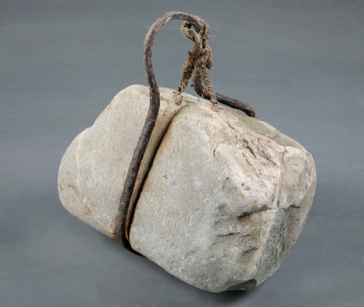En tung stein med et jernbeslag rundt seg som håndtak. Tau til ilen.