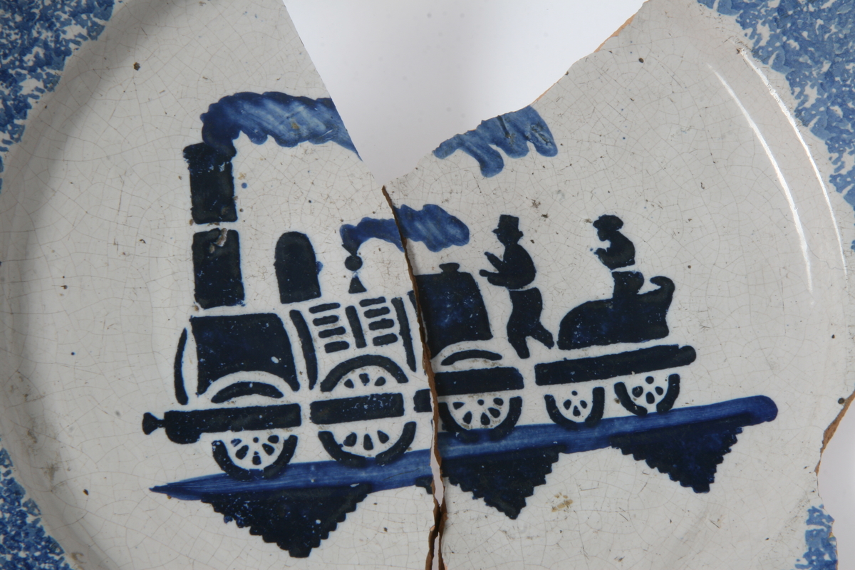 Fajanse, blå dekor: damplokomotiv med vogn. 2 deler, flere mangler.